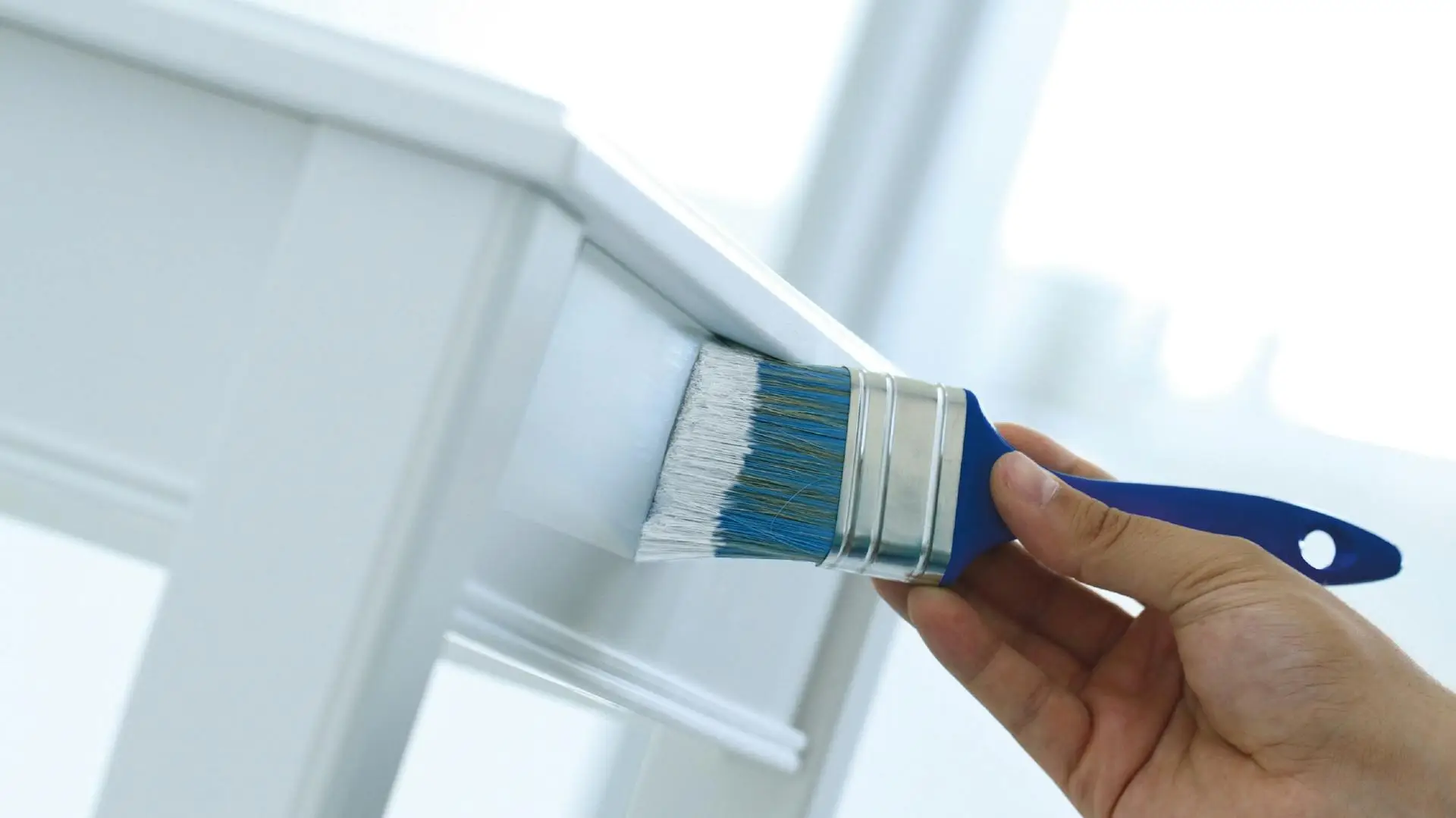 Man painting a chair white with a brush